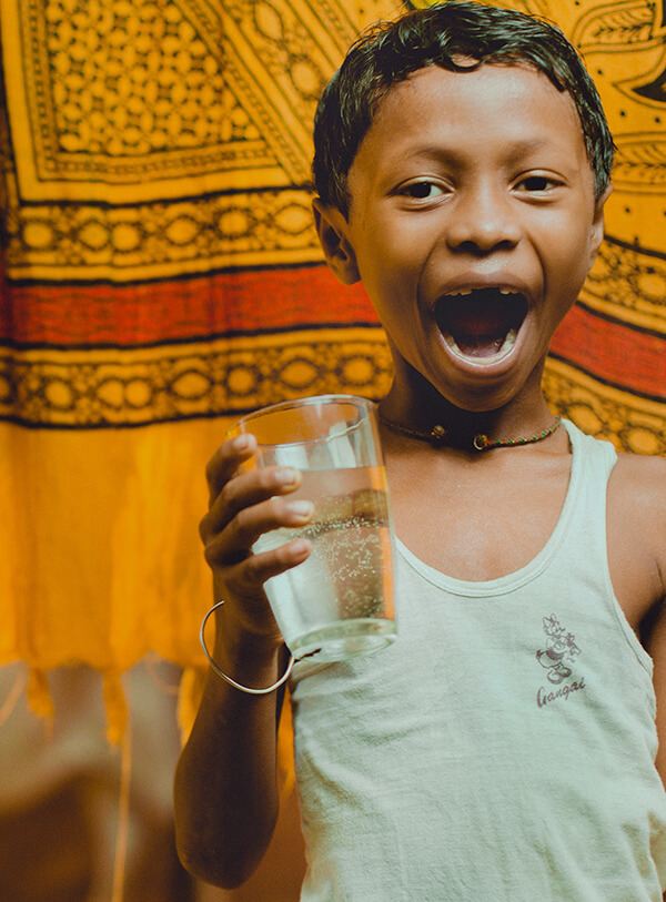 Smiling child joyfully holding a glass of clean water